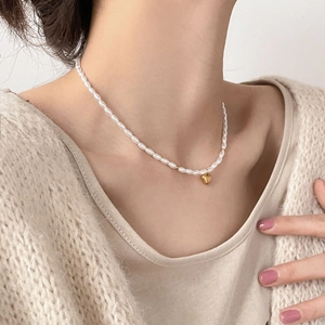 Collier élégant en perles de riz avec pendentif cœur doré porté par un mannequin