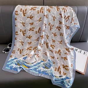 Elegant autumn silk shawl featuring fall maple leaves and Great Wave art prints on a sofa