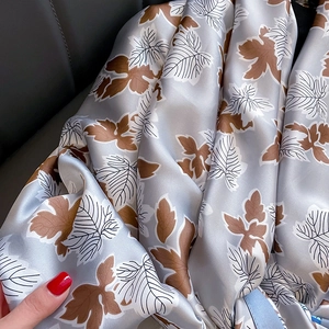 Satin scarf for women with brown leaf print and elegant soft drape on grey background