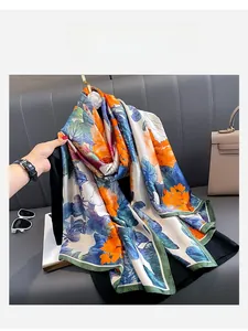 Detail of floral printed silk scarf in ivory and orange draped over a hanger