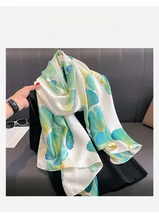 Détail d'un foulard en soie avec des motifs élégants de feuilles de ginkgo vertes et dorées