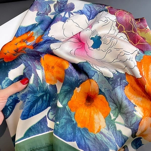 Close-up of elegant floral print silk scarf showing detailed satin texture and vibrant colors