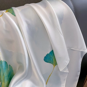 Détail de la texture en soie et du motif de feuilles de ginkgo vertes sur l'écharpe