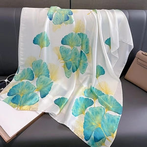 Élégante écharpe en soie avec feuilles de ginkgo jaunes et bleues sur fond en cuir gris