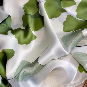 Close-up of silk-like scarf with elegant green ginkgo leaf patterns and soft luster