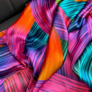 Close-up of colorful silk scarf showing vibrant pleated patterns and satin texture