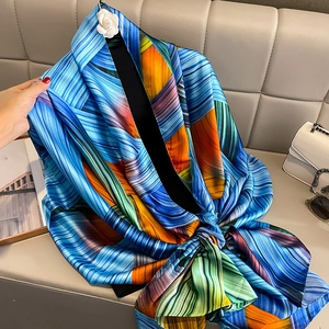 Detail of silk scarf with geometric patterns in blue and orange draped with accessories