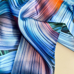 Close-up of vibrant satin scarf showing soft drape and abstract colorful flow patterns