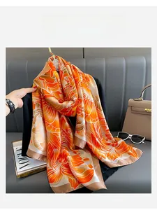 Détail d'un foulard en soie aux motifs floraux orange et bordures marron élégantes