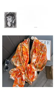 Détail d'un foulard en soie orange avec imprimés floraux et accessoires de mode