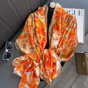 Élégant foulard en soie à imprimé floral orange drapé sur un support de luxe chic