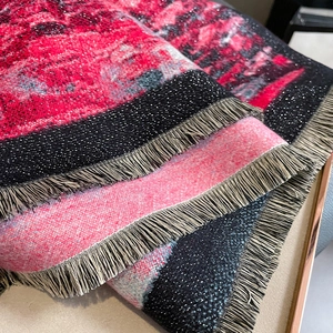 Close-up of red and black scarf fabric with shimmering metallic fibers and tassels
