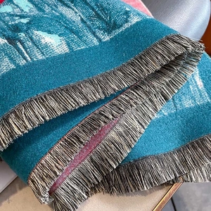 Dettaglio della sciarpa verde acqua con trama jacquard e morbide frange decorative
