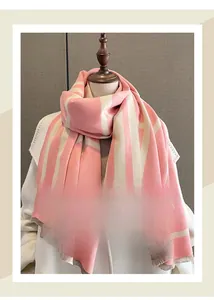 Detail of pink and beige geometric winter scarf with fringe trim on a mannequin