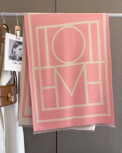 Close-up of pink and beige geometric HOME letter knit scarf with fine tassel fringe details