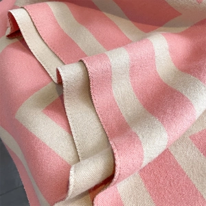 Detailed close-up showing the soft thick knit texture of pink and beige striped scarf