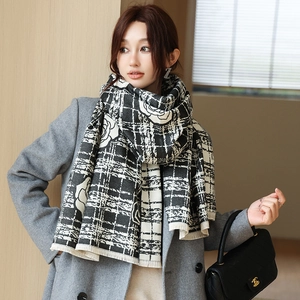 Detail of winter scarf with black and white plaid floral pattern and fringed edges