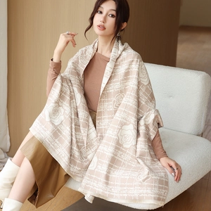 Close-up of thick warm shawl featuring white rose patterns and delicate tassel edges