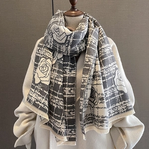 Detail of gray and white cashmere-like scarf with large rose patterns and fringe trim