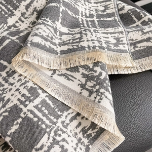 Detail of grey and white geometric plaid cashmere scarf with soft beige fringe tassels