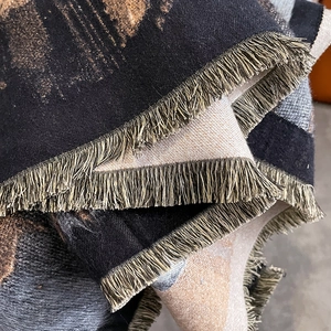 Close-up of thick cashmere-like scarf showing luxury black gold weave and long tassels