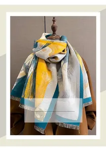 Close-up of yellow and blue abstract pattern scarf with fringe on brown coat