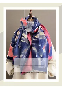 Détail d'une écharpe épaisse bleu marine avec motifs floraux et finitions à franges