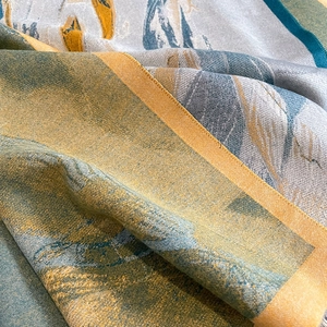 Macro shot of thick cashmere-like scarf showing dense jacquard weave and golden textures