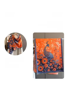 Detailed pattern of an orange and blue cashmere shawl with peacock art and soft tassels