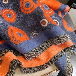 Thick cashmere-like scarf with geometric orange concentric circles and blue tassels