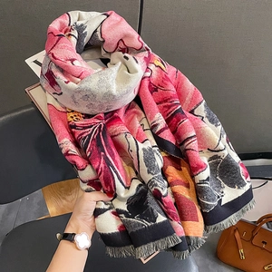 Thick floral print cashmere-feel scarf with tassels draped over a black chair for winter