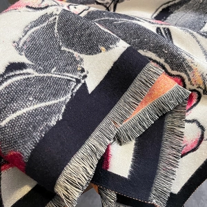 Close-up of thick floral cashmere-like scarf showing detailed fringe edges and woven texture