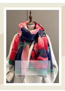 Detailed view of winter scarf with red floral prints and tassel fringe on a white coat