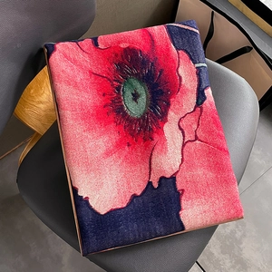 Winter scarf with red poppy floral print and metallic edges on a leather seat