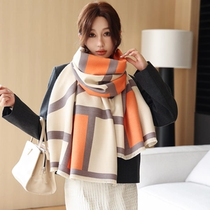 Detail of color-block cashmere-like shawl with orange and grey geometric patterns and fringe