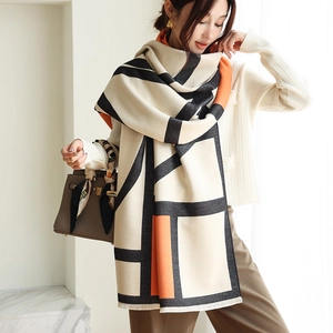 Detail of soft cashmere-like scarf showing orange and black geometric blocks and thick texture