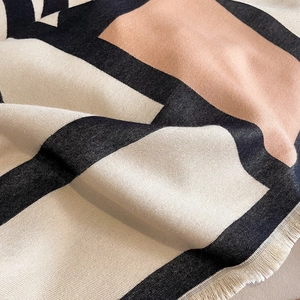 Detailed view of the thick geometric patchwork scarf featuring fine tassel edge details