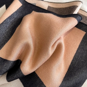 Close-up of thick cashmere-like scarf showing soft geometric patterns and edge stitching