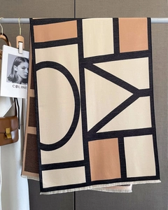 Detail of geometric pattern shawl with fine fringe in earth tones and soft cashmere feel