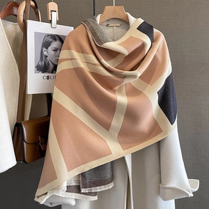 Detailed view of geometric patterned cashmere pashmina with fringe on a white coat