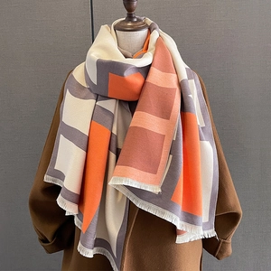 Detail of color-block geometric scarf with short fringe on dark wool coat background