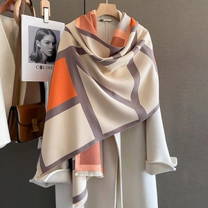 Thick geometric color-block shawl with fringe over white coat, featuring orange and beige