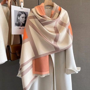 Detail of color-block scarf with orange and beige geometric patterns and soft fringes