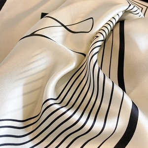Minimalist striped silk scarf featuring black geometric lines on a creamy satin fabric