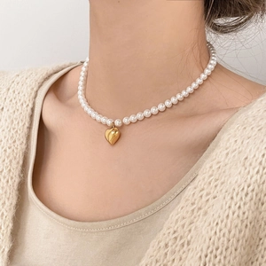 Gros plan d'un collier ras du cou en perles avec pendentif coeur doré sur le cou d'un mannequin