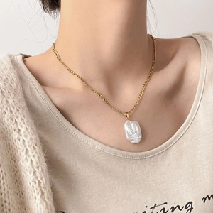 Détail d'un grand pendentif perle baroque irrégulière sur une fine chaîne dorée