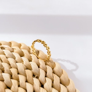 Detailed view of a gold star-shaped hollow band ring on a natural woven straw mat