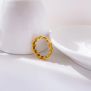 Close-up of golden chunky twisted braided ring resting on a white ceramic cup