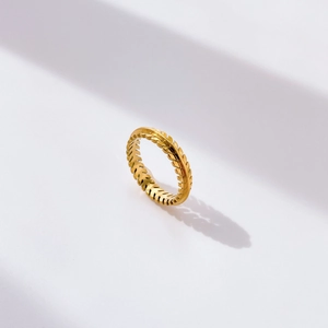 Detail of 18K gold ring with leaf relief texture on a clean white background