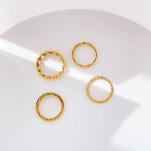Minimalist gold olive leaf and star rings set displayed on a white geometric stage